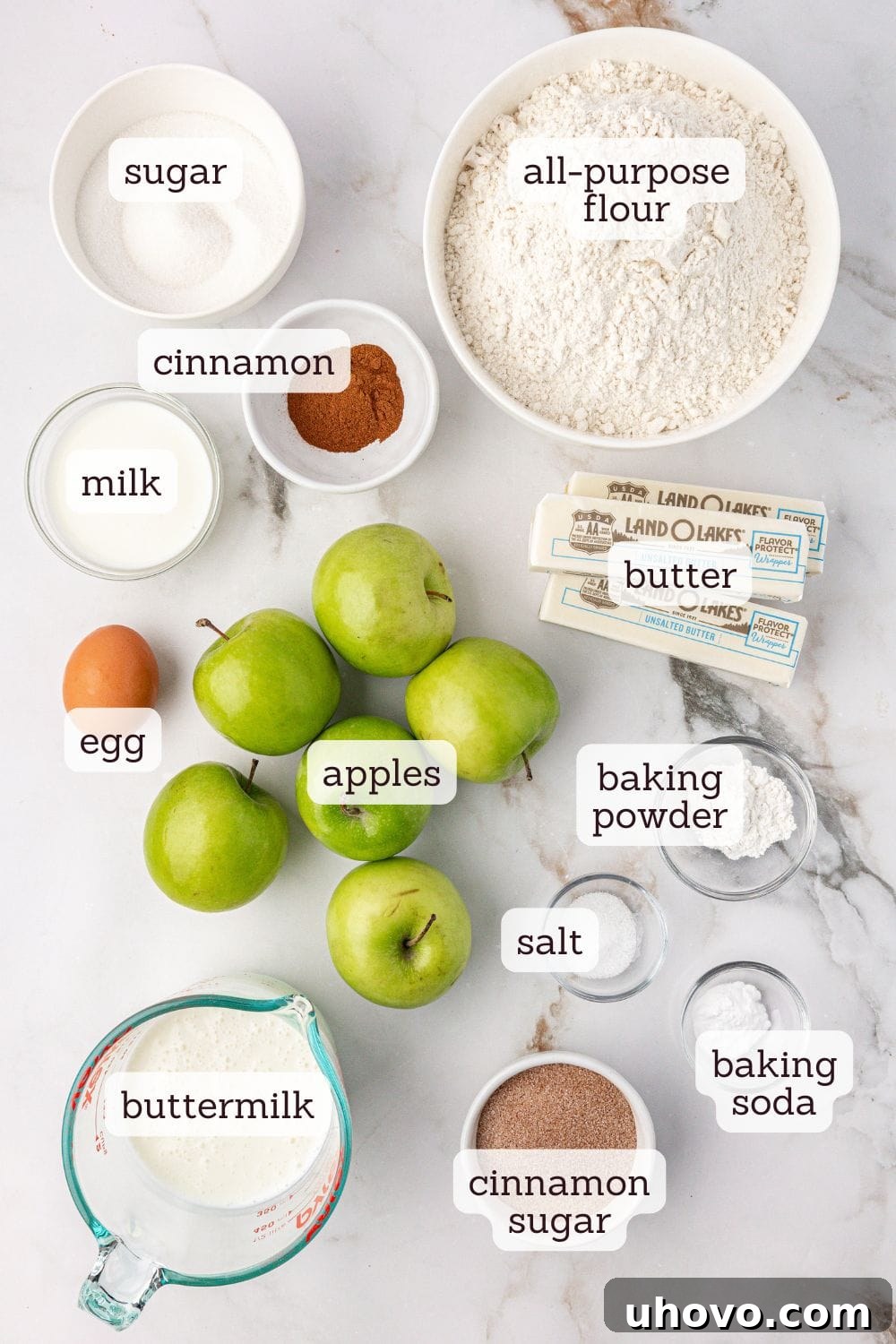 Overhead view of labeled ingredients for apple cinnamon scones on a wooden surface.