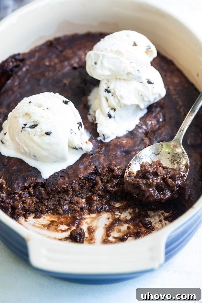 A close-up shot of a magnificent ice cream-topped Brownie Chocolate Pudding Cake, presented in a charming blue oval baking dish, showcasing its rich texture and irresistible appeal.
