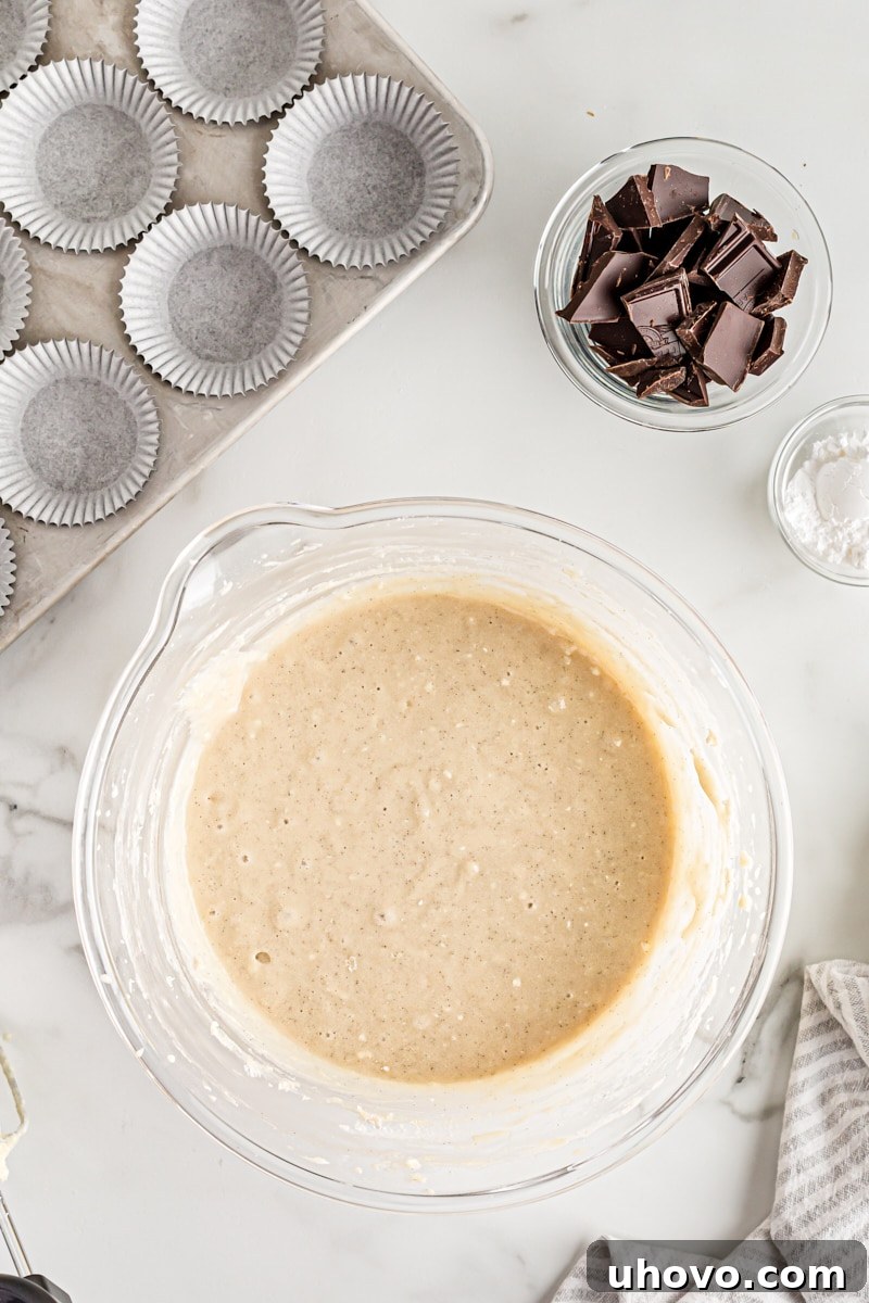 Overhead view of finished cupcake batter in a mixing bowl, alongside a small bowl of bittersweet chocolate chunks.