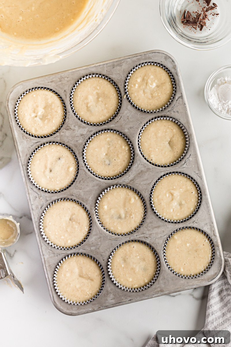 Overhead view of chocolate-filled cupcakes in a muffin tin, ready to be baked.