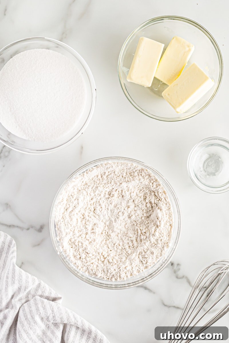 Overhead view of bowls containing dry ingredients, granulated sugar, and softened butter for cupcake batter.