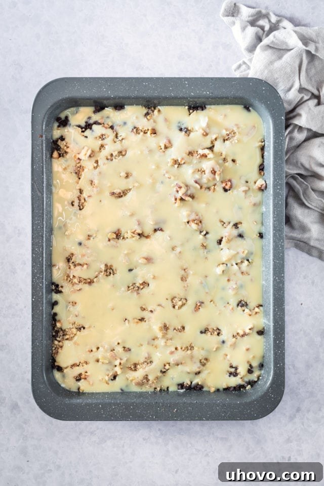 overhead view of Caramel Coconut Pecan Brownie batter in a rectangular baking pan, neatly assembled and ready to be placed in the oven