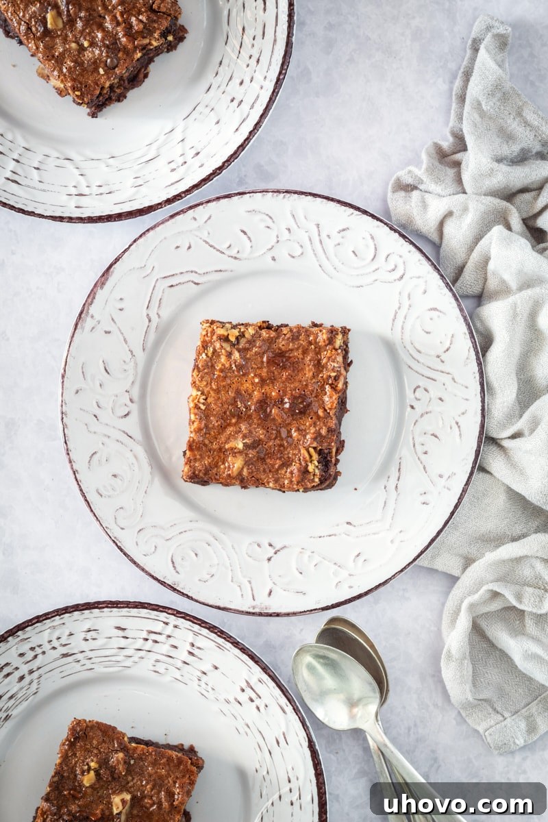 Overhead view of several caramel coconut pecan brownies artfully arranged on white plates, ready for serving.
