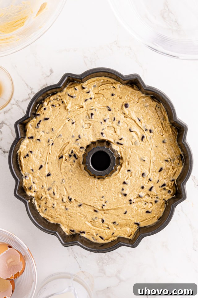 An overhead view of the chocolate chip Bundt cake batter smoothly spread in a Bundt pan, poised for baking in the oven.