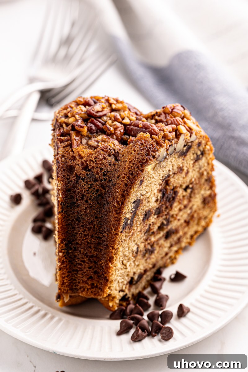 A close-up of a single slice of chocolate chip Bundt cake on a white plate, highlighting its rich brown sugar crumb and generous chocolate chunks.