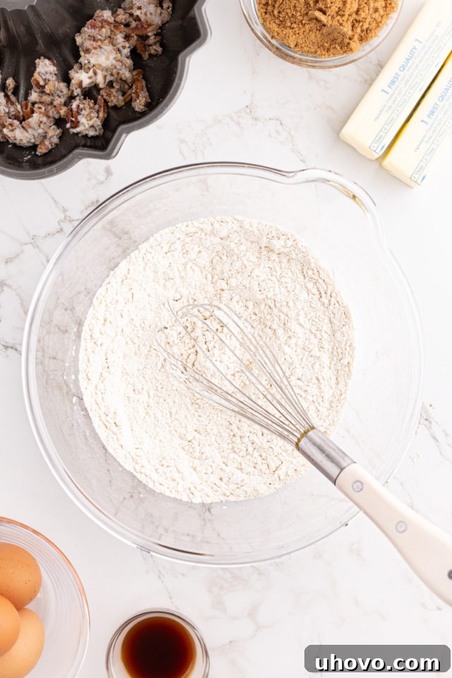 A close-up, overhead view of the mixed dry ingredients for the chocolate chip Bundt cake, perfectly combined in a glass bowl.