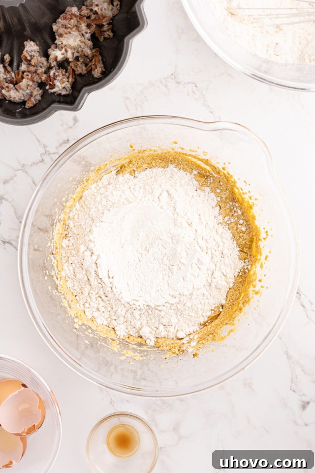 The dry ingredients mixture being gradually added to the wet ingredients in a glass mixing bowl, signaling the next stage of batter preparation.