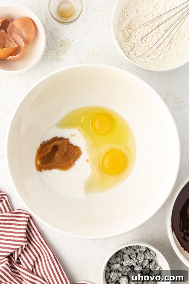 Granulated sugar, eggs, and vanilla extract in a large mixing bowl, ready to be beaten for the wet ingredients.