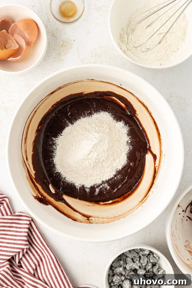 Dry flour and salt mixture being slowly added to the wet brownie batter, ready for gentle mixing.