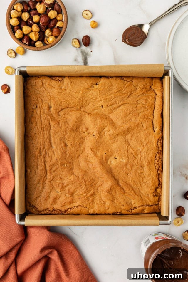 A freshly baked batch of hazelnut blondies, golden brown and perfectly set, cooling gently in their square baking pan on a wire rack.