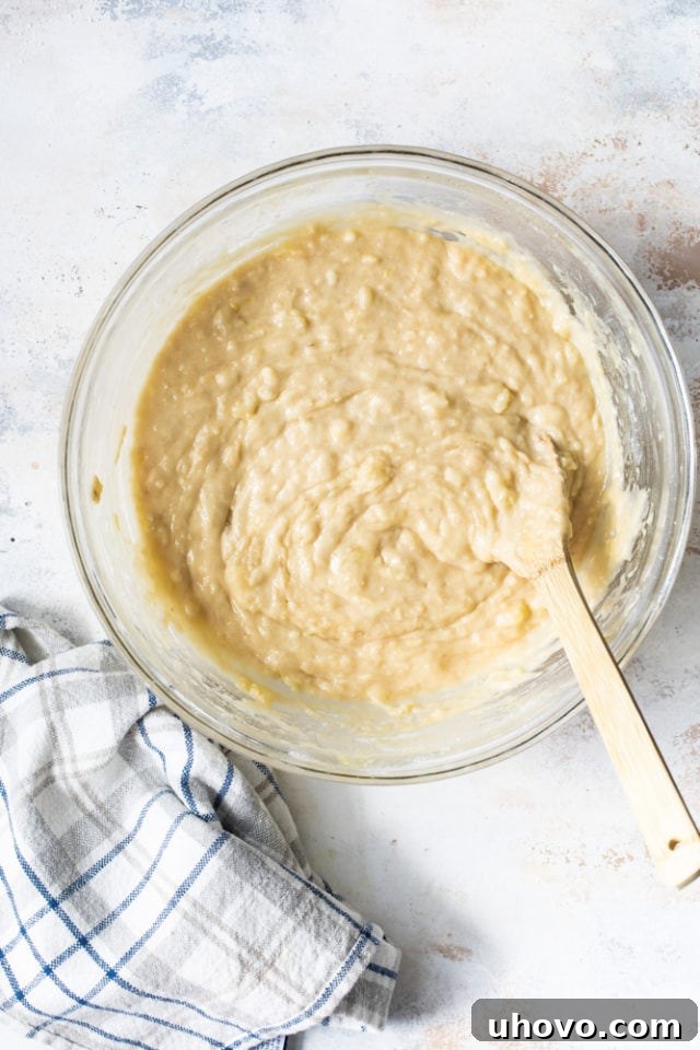 Overhead view of cake batter in glass bowl with wooden spoon
