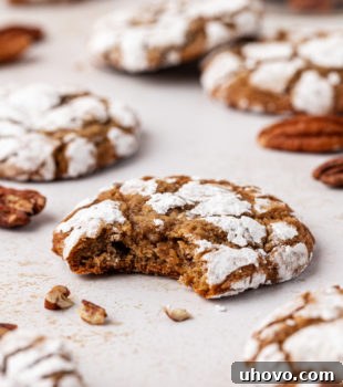 A close-up of a bitten brown sugar crinkle cookie, revealing its moist, chewy interior and nutty pecans.
