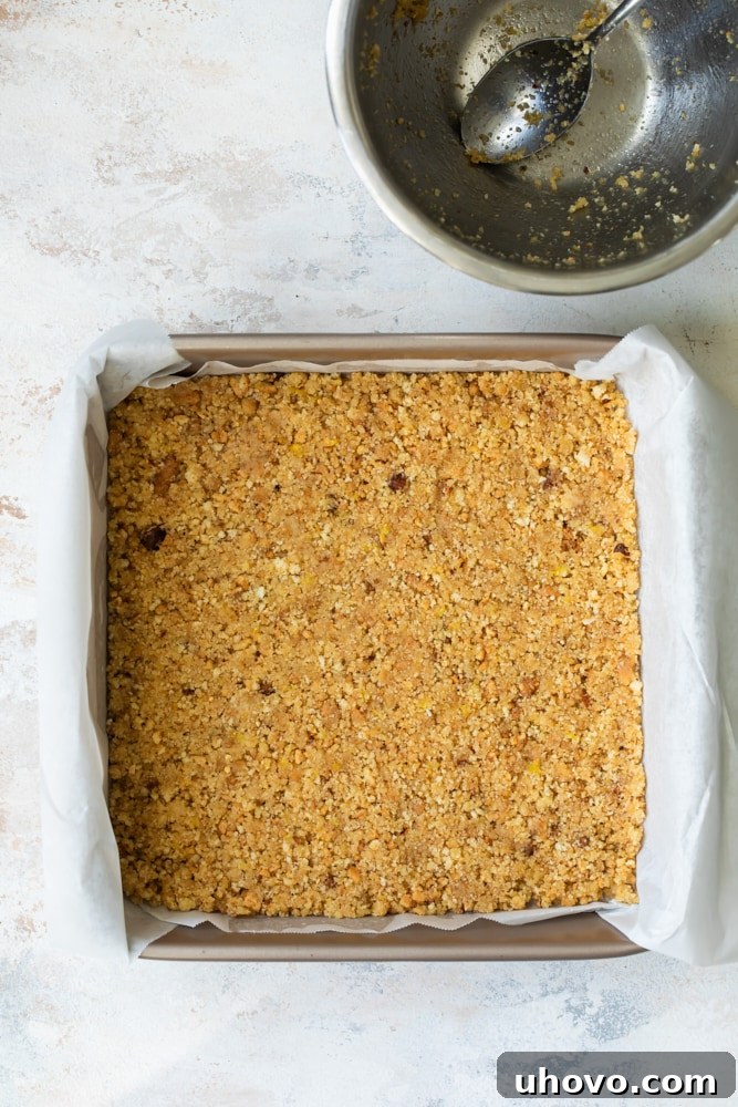 Biscotti crust mixture pressed into a parchment-lined square baking pan