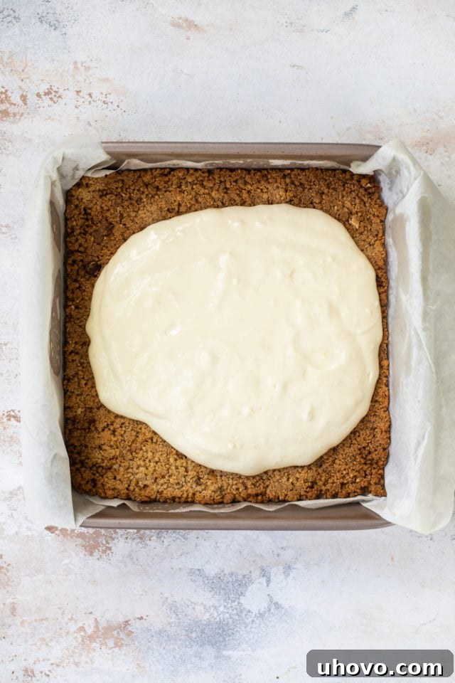 Limoncello cheesecake filling poured over the biscotti crust in a baking pan