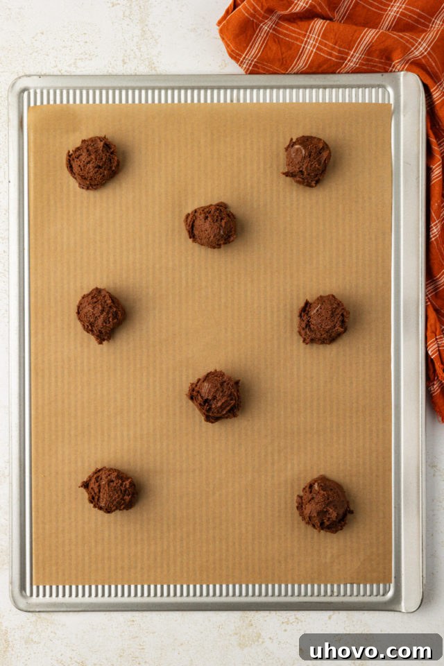 chocolate peanut butter cookie dough portioned into balls on a parchment-lined baking sheet