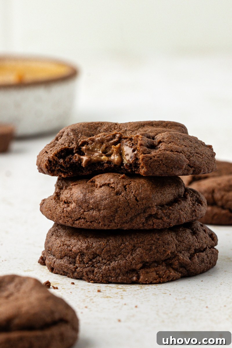 a stack of three chocolate peanut butter cookies with a bite missing from the top cookie