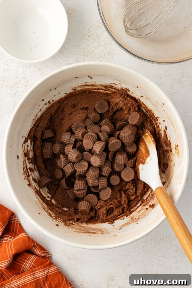 overhead view of mini peanut butter cups added to chocolate cookie dough