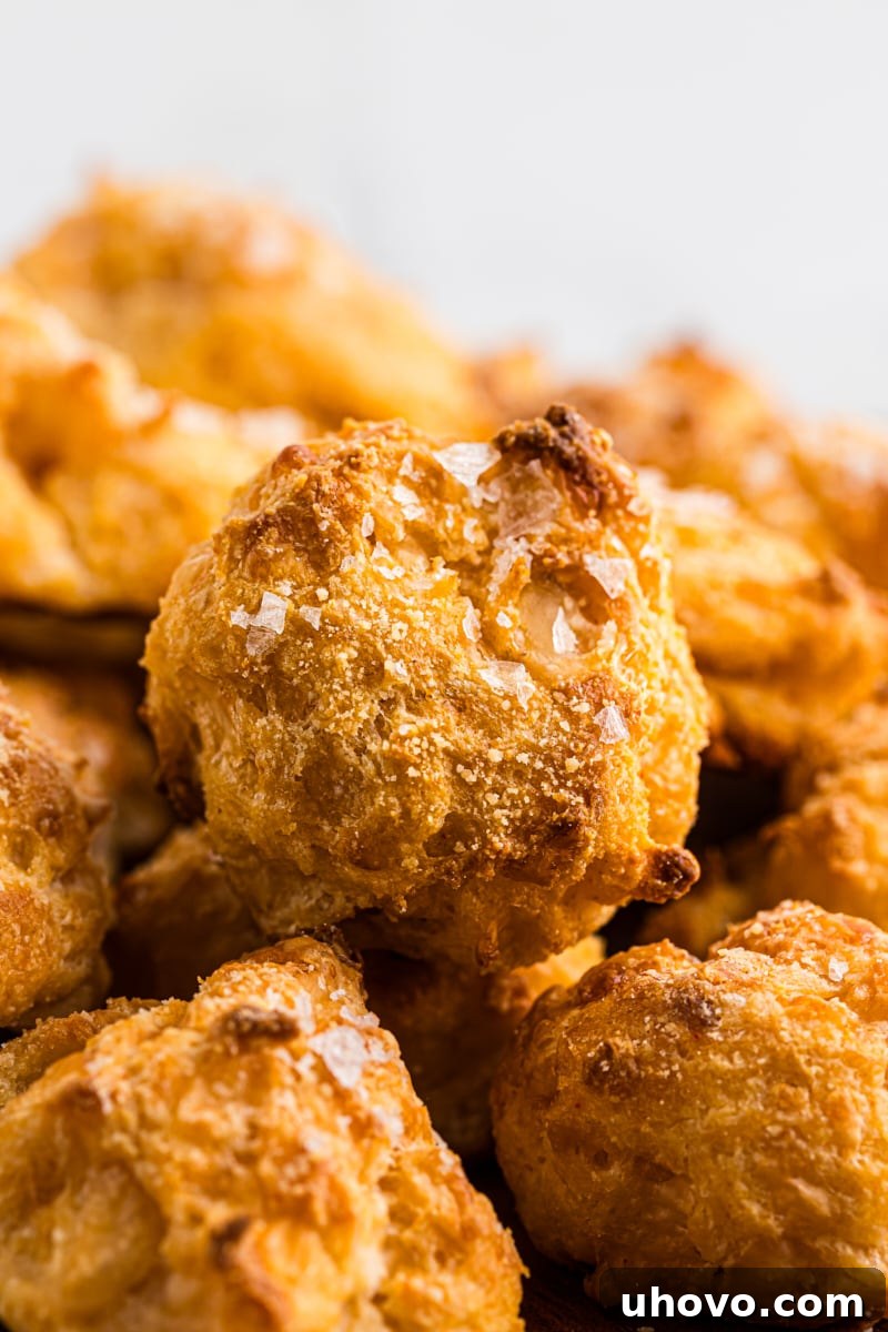 Closeup shot of freshly baked gougères, sprinkled with coarse sea salt, showcasing their golden-brown and irregular shape.
