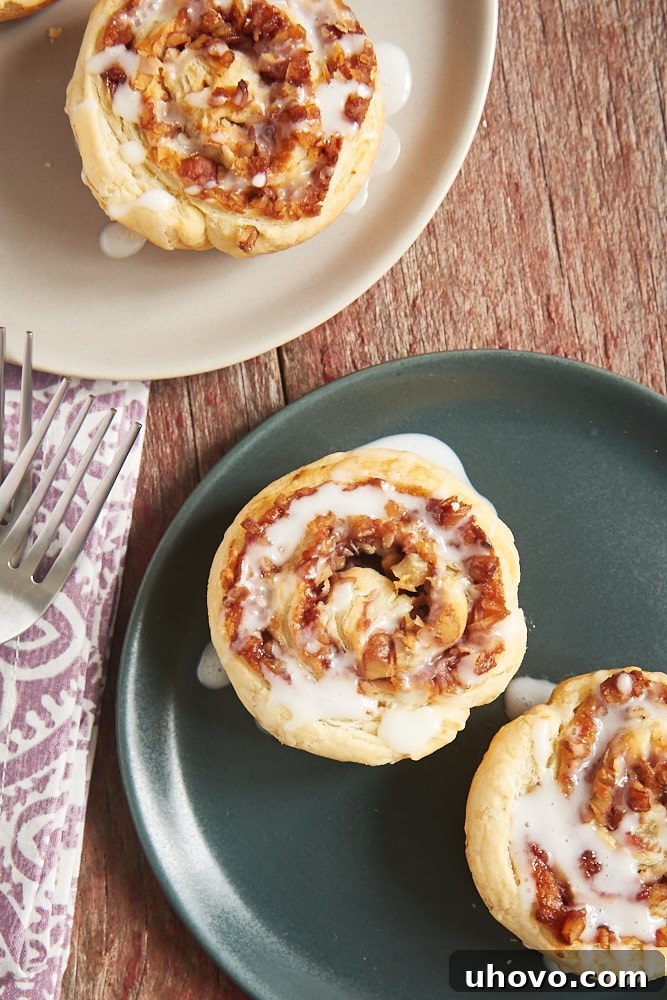 Overhead view of several Berry Cream Cheese Pastry Swirls arranged neatly on a light gray plate, showing their intricate spiral pattern and the glossy glaze.