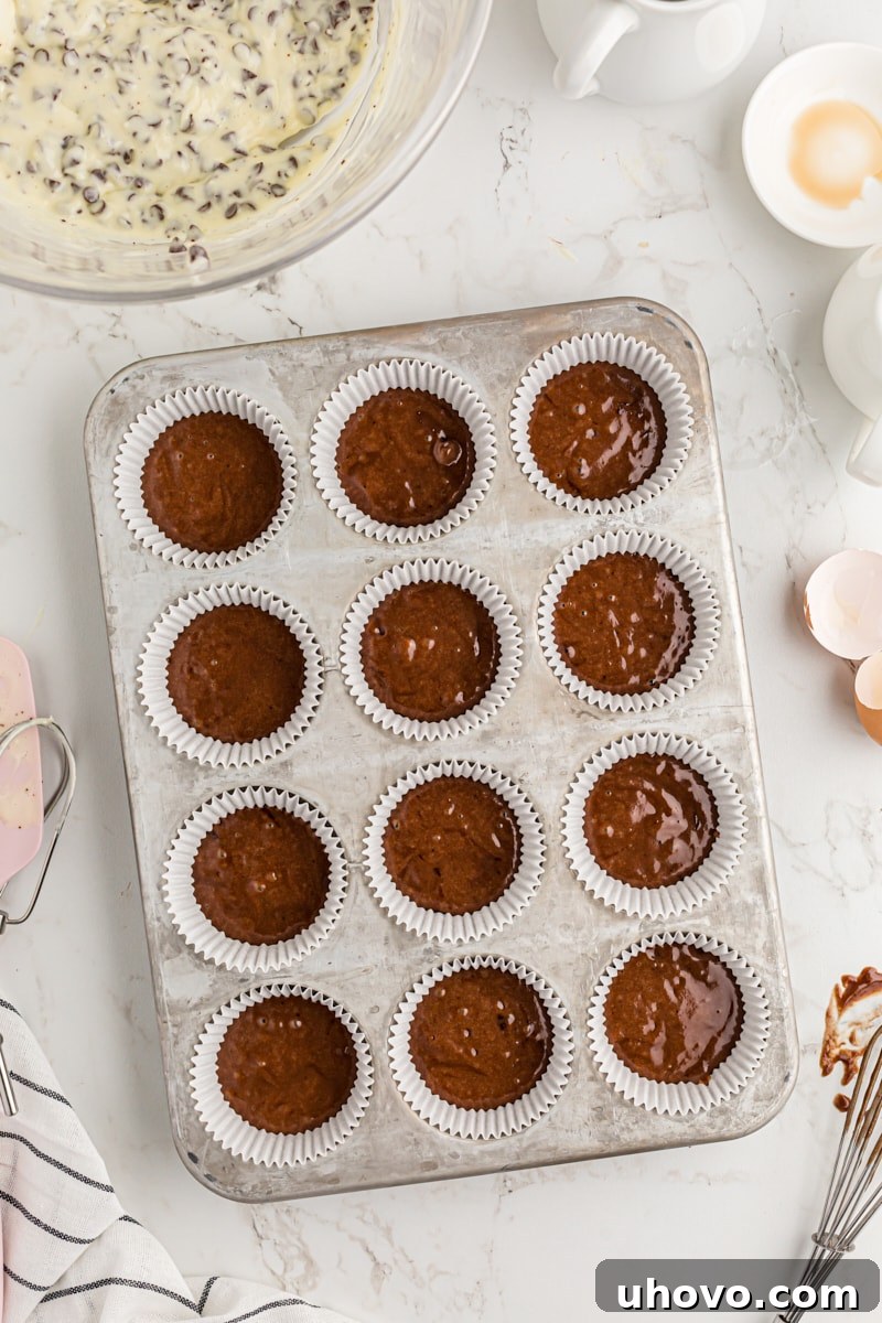 Muffin cups filled 1/3 of the way with chocolate batter.
