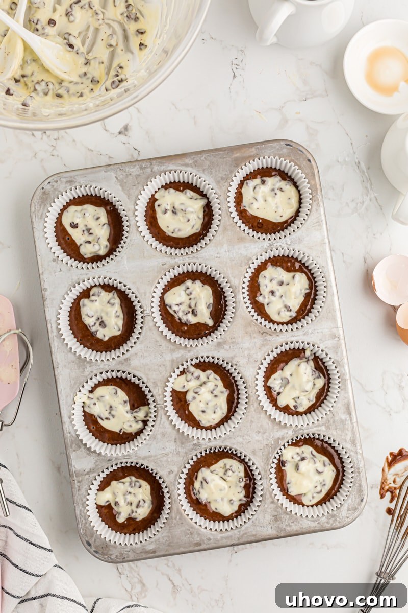 Adding cream cheese filling to the muffin tins.