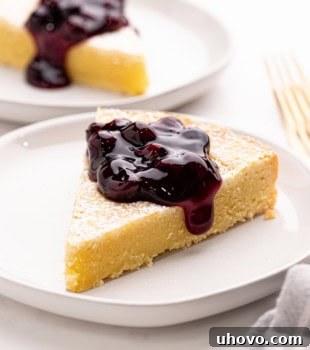 A delightful pair of Almond Gâteau Breton slices, one topped with luscious blueberry compote, elegantly arranged on white plates, beckoning you to savor this classic French almond cake.