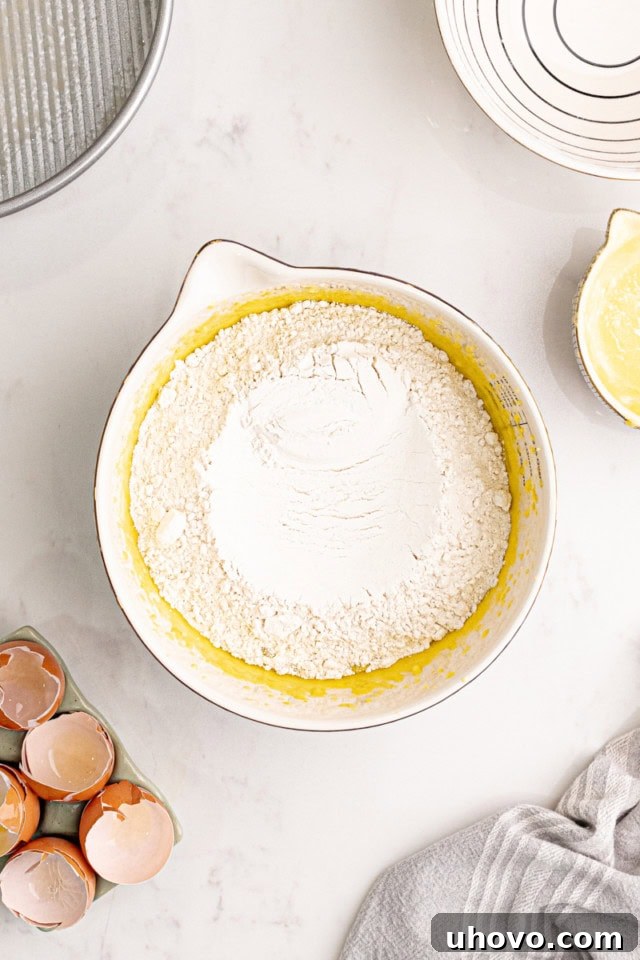 All-purpose flour being gently folded into the thick, luscious almond cake batter in a large mixing bowl, ensuring a tender crumb.