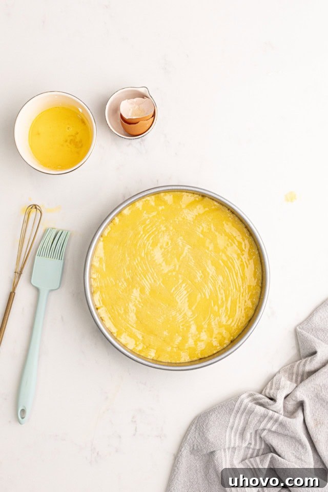 The dense almond gâteau Breton batter spread evenly into a prepared round cake pan, ready for the application of an egg wash.