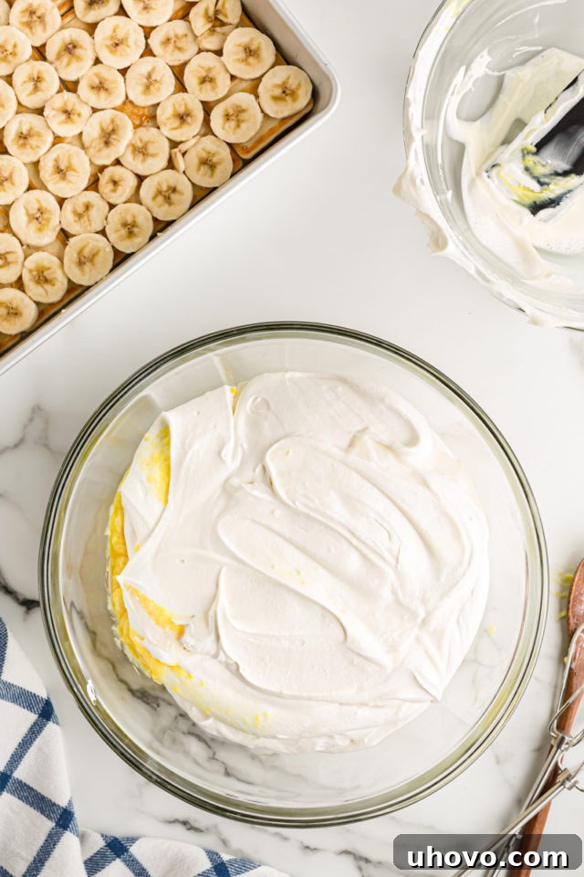 Overhead view of the creamy banana pudding mixture in a clear glass mixing bowl, ready to be spread.