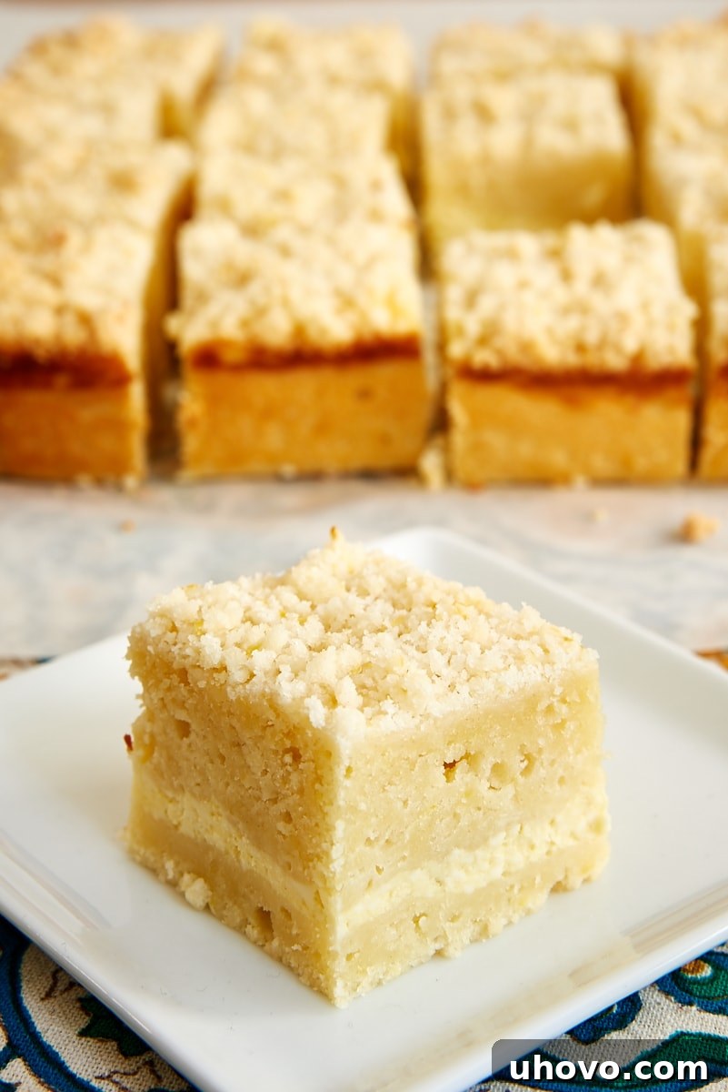 slice of Lemon Cream Cheese Coffee Cake on a white plate with more slices of cake in the background
