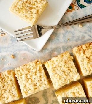 overhead view of slices of Lemon Cream Cheese Coffee Cake on a white plate and on white parchment paper