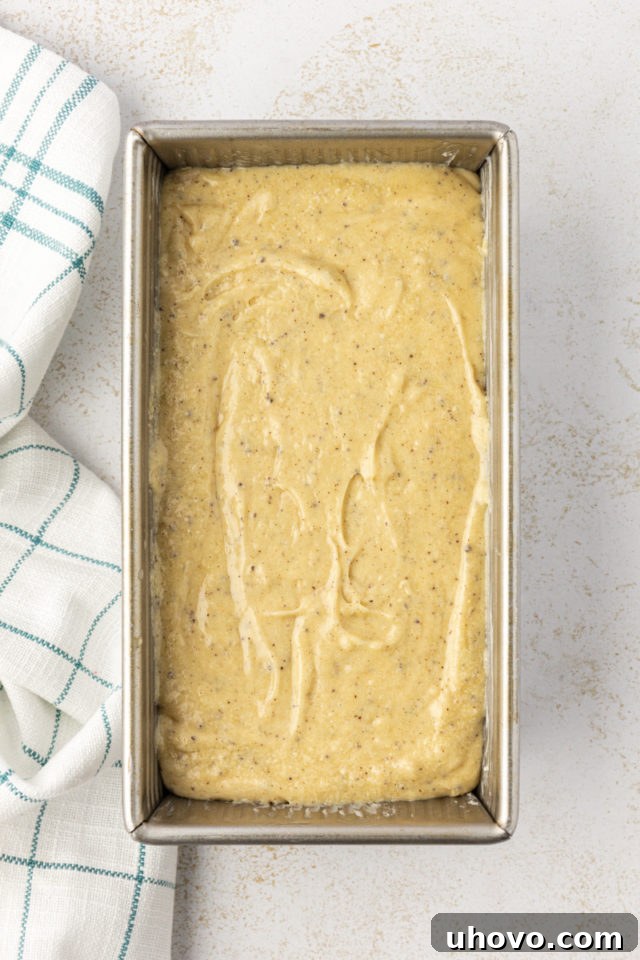 Overhead view of brown butter pound cake batter spread evenly in a loaf pan, ready for baking.