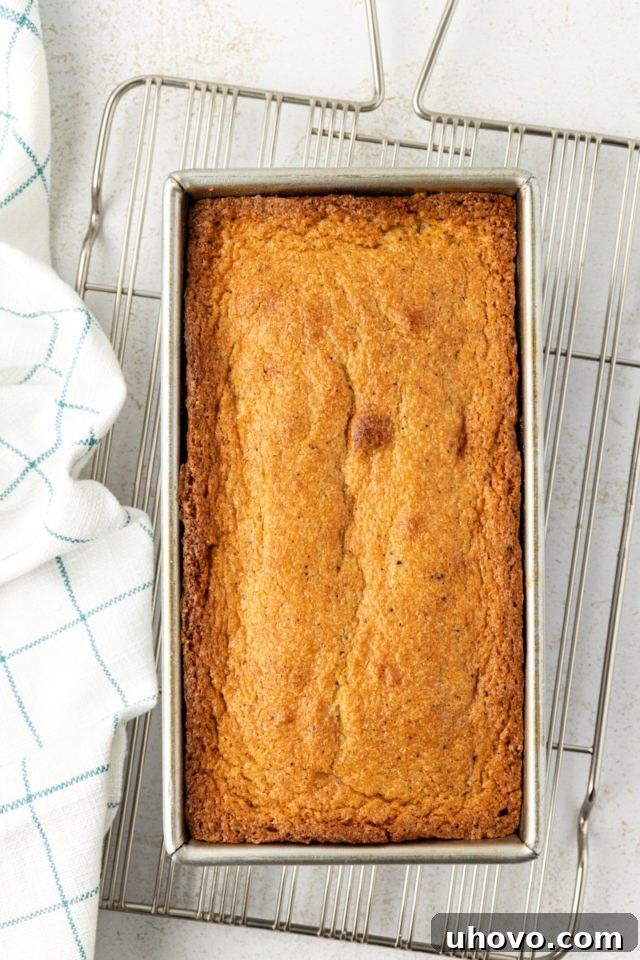 Overhead view of a freshly baked brown butter pound cake in a loaf pan, resting on a wire rack.