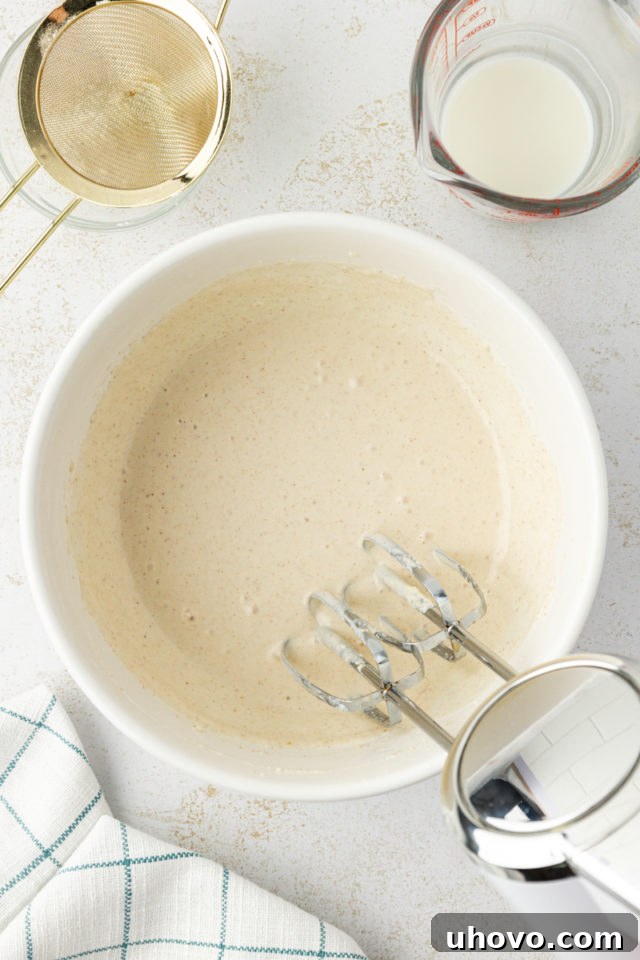 Overhead view of the finished brown butter glaze in a mixing bowl, showing its thick, pourable consistency.