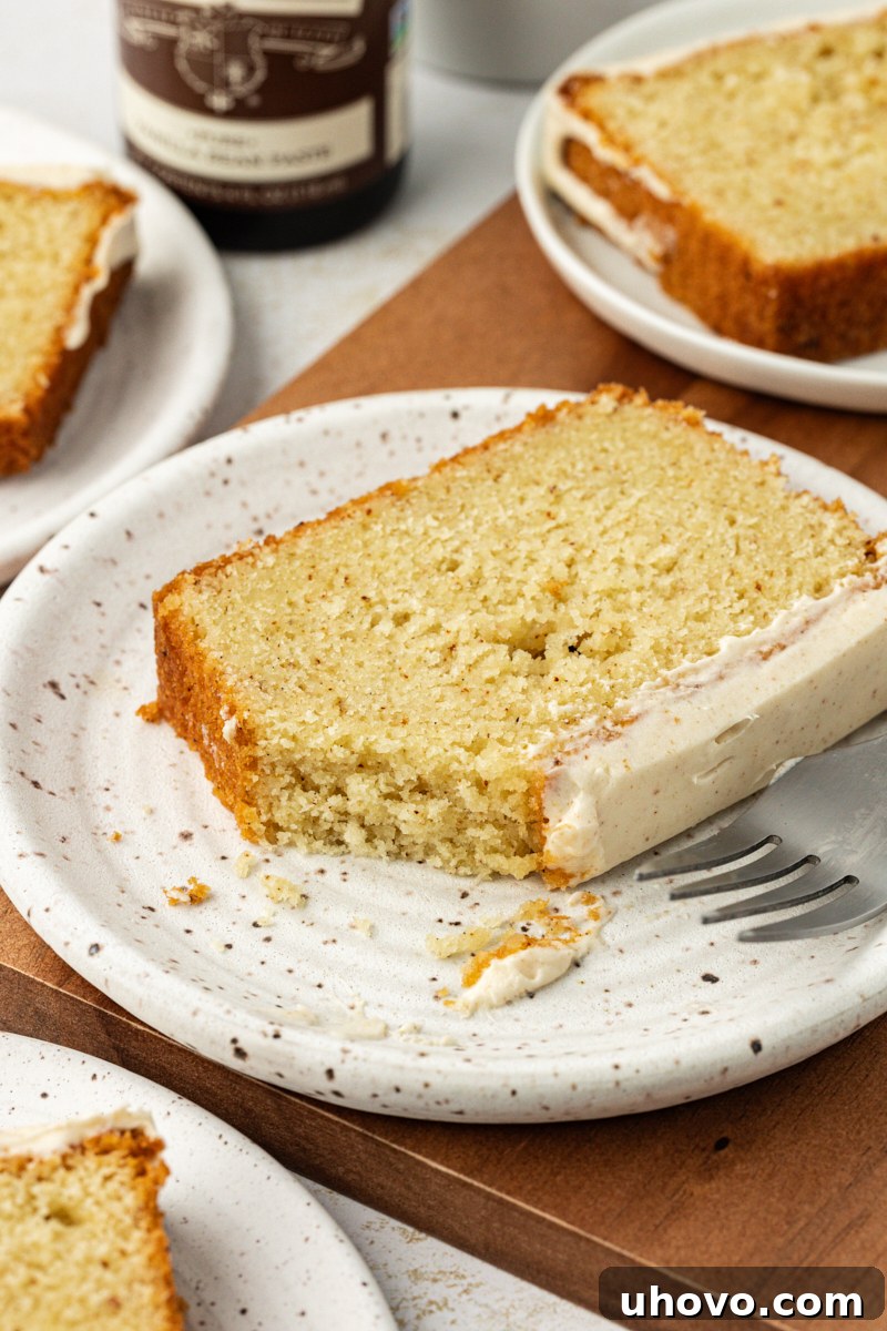 A close-up view of a slice of brown butter pound cake with a bite taken out, resting on a white plate, highlighting its tender crumb.