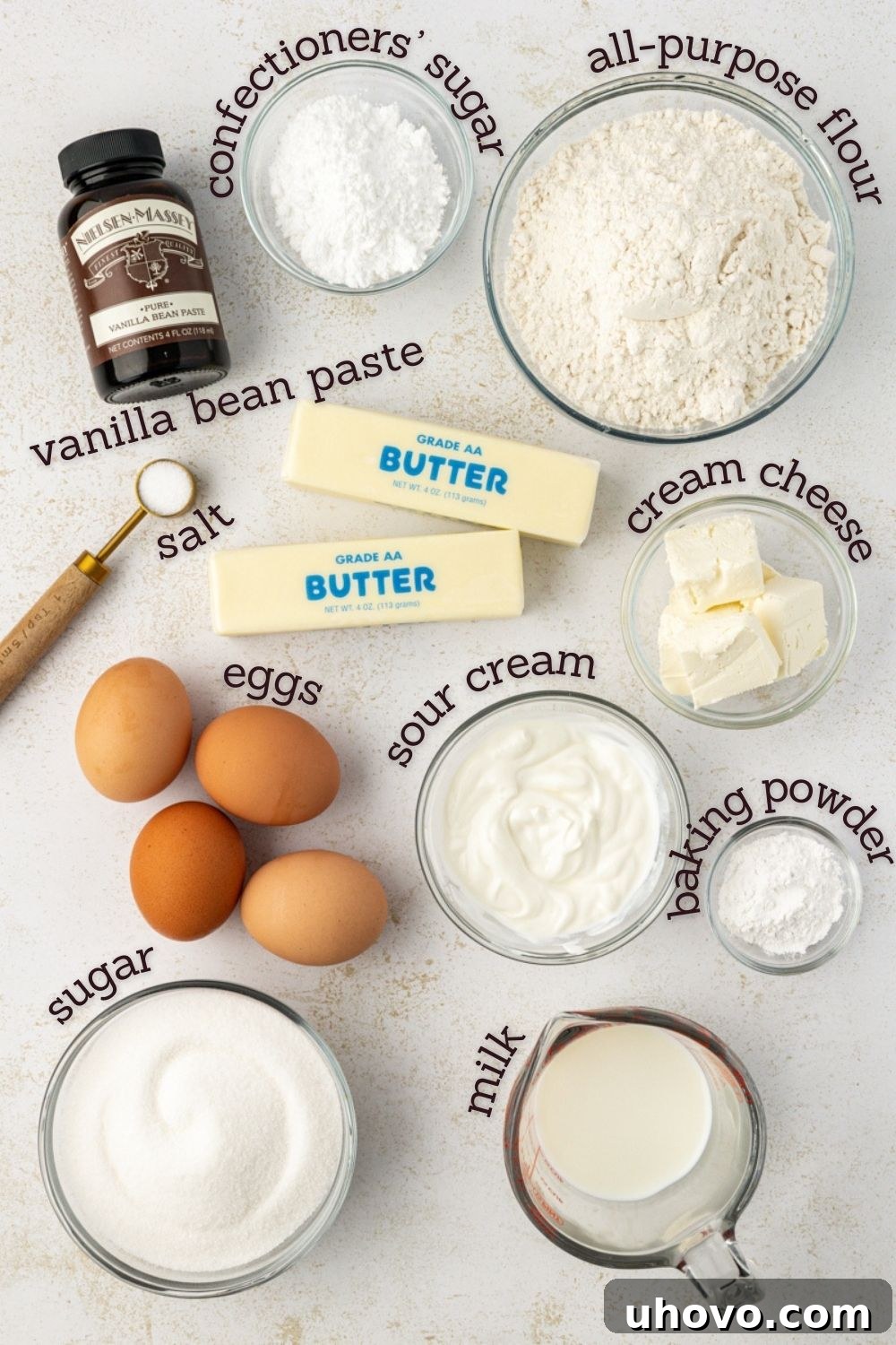 An overhead view of the ingredients for brown butter pound cake laid out on a surface, including butter, flour, sugar, eggs, and vanilla bean paste.