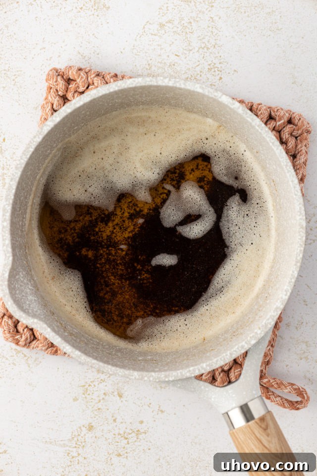 Overhead view of browned butter in a saucepan, showing golden liquid and toasted specks at the bottom.