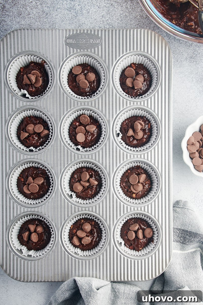 Overhead view of brownie batter topped with chocolate chips in muffin tin