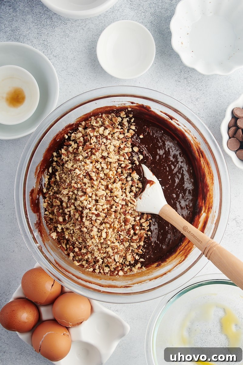 Overhead view of nuts being stirred into brownie batter
