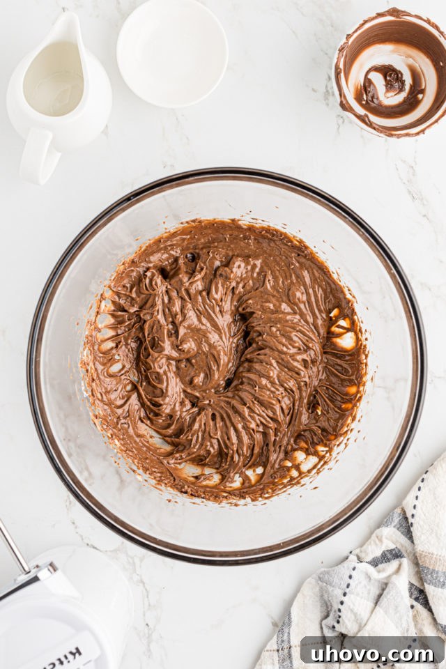 Overhead shot of the mascarpone and Nutella mixture being whisked together until smooth and fully combined in a glass bowl.