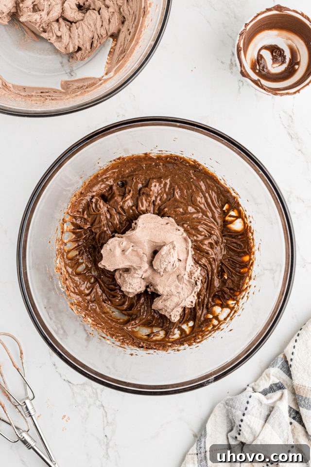 Overhead view of a portion of whipped cream being added to the chocolate-mascarpone mixture, ready to be lightened.