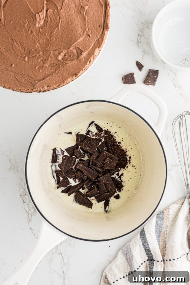 Overhead view of finely chopped bittersweet chocolate added to warm heavy cream in a small saucepan.