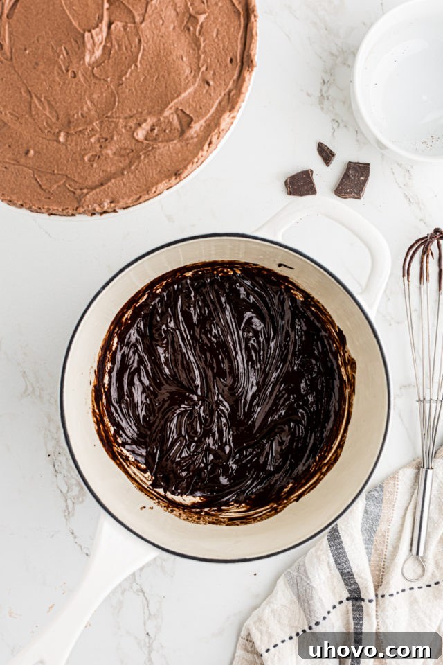 Overhead view of chocolate ganache in a saucepan, being whisked until smooth and glossy.