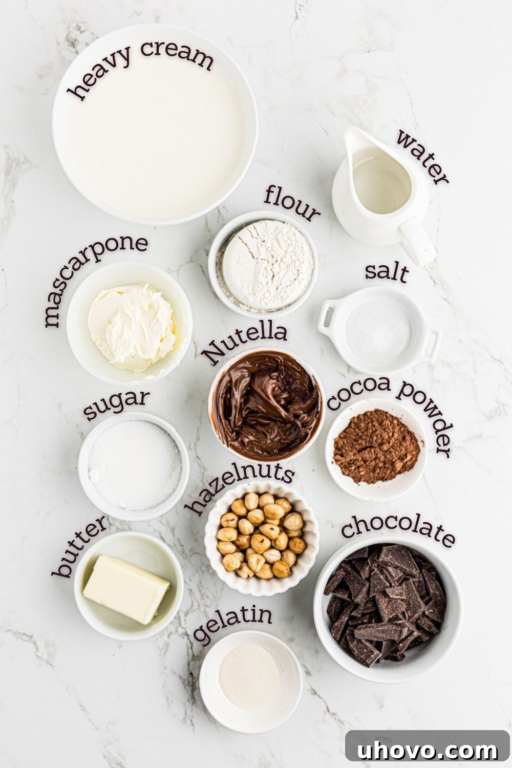 Overhead view of various ingredients laid out for making Chocolate Hazelnut Mousse Cake, including hazelnuts, chocolate spread, and cream.