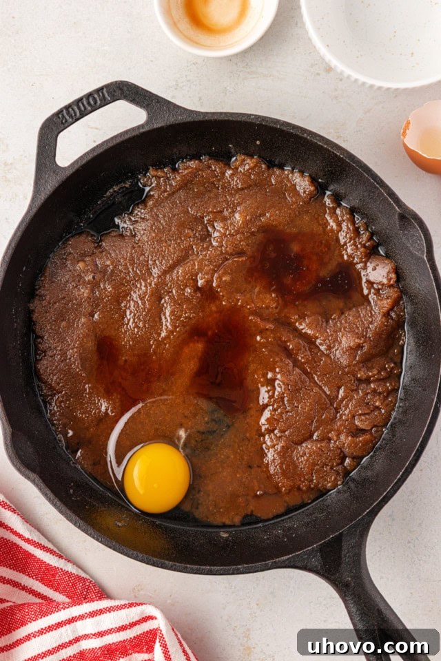 overhead view of egg and vanilla added to cooled butter and brown sugar mixture in a cast iron skillet