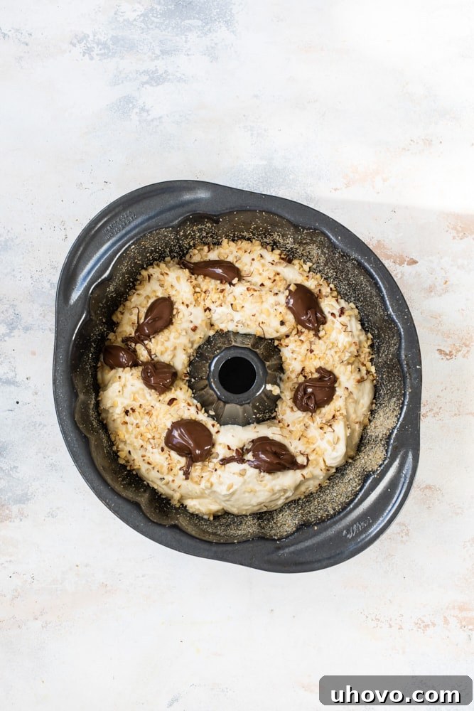 Overhead view of Nutella dropped on bundt cake batter in pan