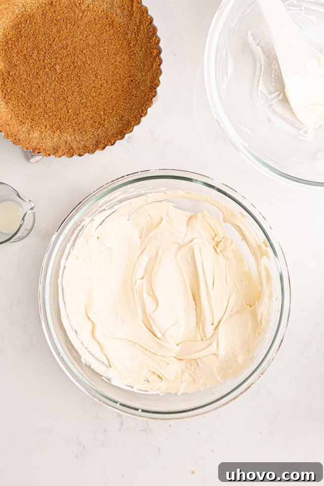 An overhead view of the fully combined lemon cream pie filling in a clear glass mixing bowl. The filling is light, fluffy, and smooth, showcasing its ready-to-spread consistency after the whipped cream has been gently folded in.