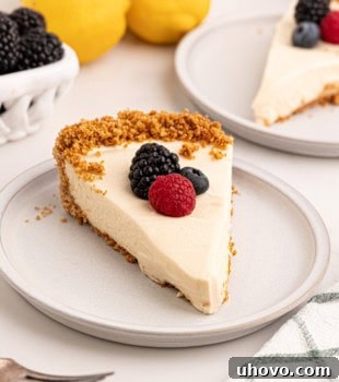 A delectable slice of lemon cream pie, elegantly topped with a scattering of fresh berries. In the background, more pie, zesty lemons, and vibrant berries create a visually appealing and tempting dessert tableau.