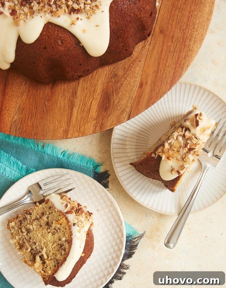 A close-up of a delightful slice of Italian Cream Bundt Cake, showcasing its moist, fluffy texture, generously studded with toasted coconut and pecans, and crowned with a generous swirl of creamy, dreamy glaze.