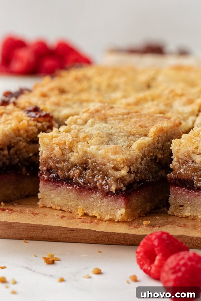 Side view of beautifully layered raspberry crumble bars on a serving board